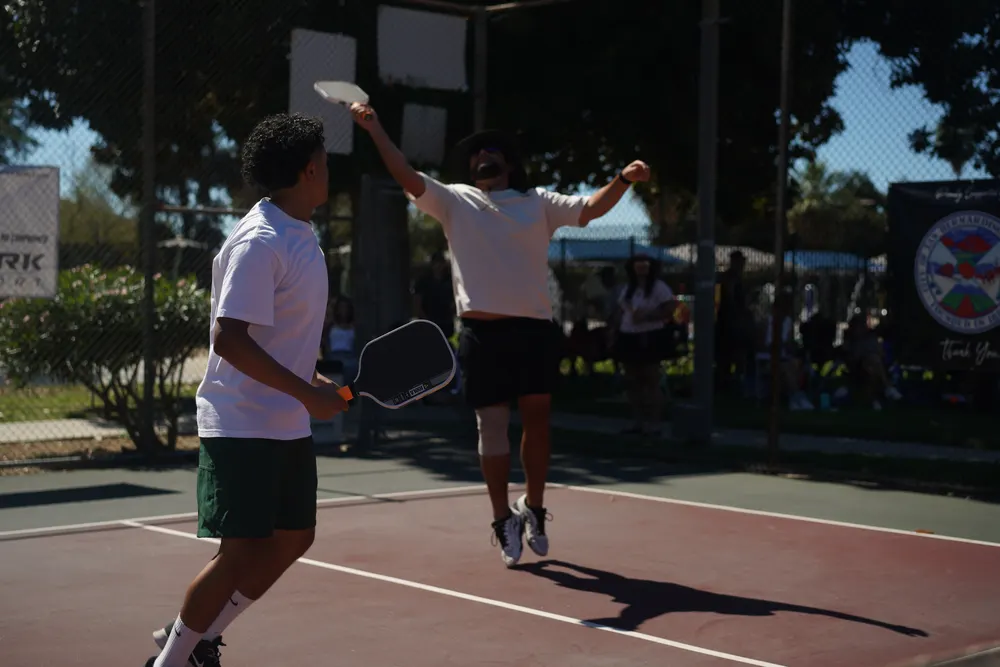 Player leaps for an overhead shot during a doubles match