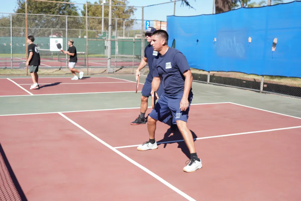Doubles team in matching navy shirts moving to the ball
