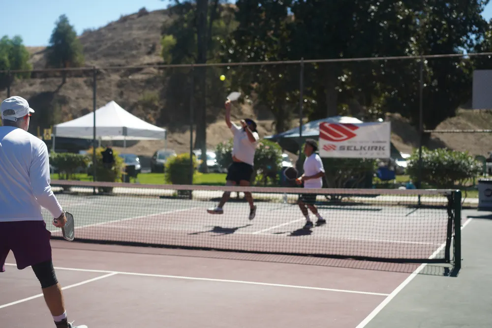 Rally at the net with sponsor banners behind the court